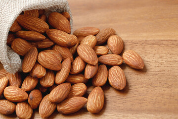 Almonds in a sack on wooden background