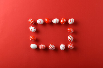 Easter backgrounds with a rectangular frame of Easter red and white eggs on a bright red background. Copy space. Flat lay, top view.
