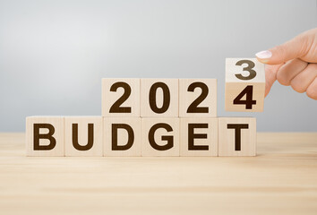 Business concept of planning 2024. Businessman flips wooden cube and changes words BUDGET 2023 to BUDGET 2024. Phrase 2024 BUDGET