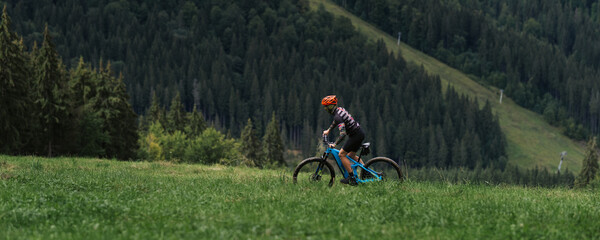 Mountain bike cyclist in sport equipment and helmet riding on rugged trails