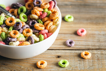 Colored breakfast cereals in a bowl on a wooden background, close up, children's healthy breakfast.