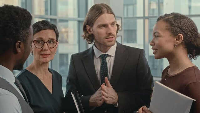 Waist up of multiethnic team of lawyers having conversation while working together in successful law firm