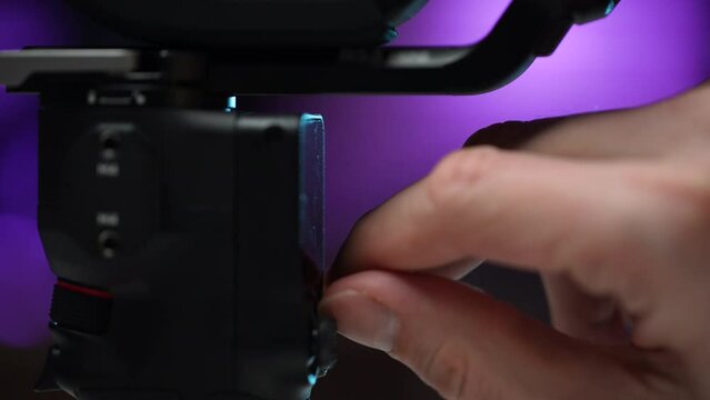 Close-up cropped shot of unrecognizable male videographer removing protective film from display of new steadicam. Stages of assembling and preparing professional modern electronic stabilizer for work.