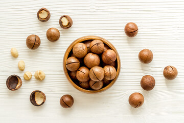 Wooden bowl of raw macadamia nuts in shell. Healthy protein snack background