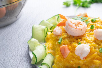 Omelet and shrimp on rice with cucumber in gray dish on concrete table. (Scrambled egg)
