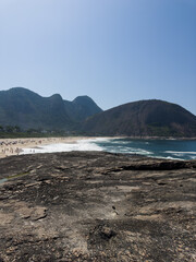 Fototapeta na wymiar View of Itacoatiara beach in Niterói in Rio de Janeiro, Brazil with its beautiful hills surrounding the beach, big waves in a sunny summer day