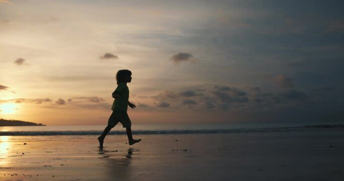 Slow motion of boy silhouette run on the beach at sunset. Concept of child dream