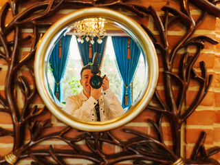 a man with a camera takes his photo in the reflection in the mirror. 