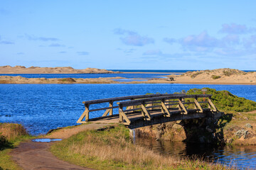 Wooden bridge over blue water in dry sandy landscape on California coast