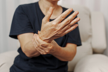 Fototapeta na wymiar Close up hands of asian senior elderly woman with parkinson's disease symptom, hand numbness, finger lock, hand pain. Mental health and elderly care concept