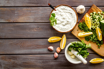 Greek dip sauce sour cream with herbs and cucumber. Cooking on kitchen table