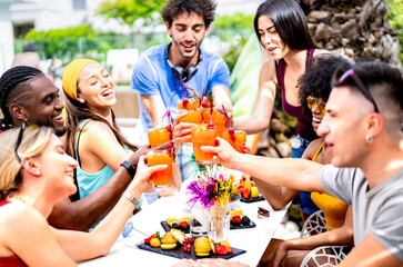 Fancy people drinking cocktails at poolside party - Young friends having fun on luxury resort - Diverse life style concept with guys and girls toasting drinks and fruit together - Bright vivid filter - 589933032
