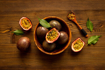 Whole and half of fresh passion fruit in wooden bowl