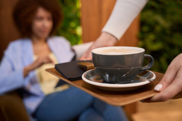 Fashionable woman getting served mug of coffee at hall