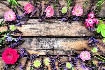 Flowers in a circle on a wooden background. Postcard for the holiday. Roses, geraniums, lavender, sage and hairy chestnuts are placed along the edges on dark boards. Background copy space, flat lay.