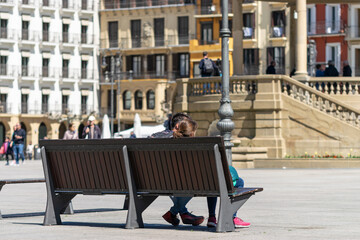 Fototapeta na wymiar Tourist couple on a bench in the sun. Castle Square, Pamplona