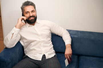 Cheerful tourist talking on smartphone in hotel room