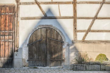Fototapeta na wymiar Fachwerkhaus mit Scheunentor und Schatten in Form eines Dreieecks
