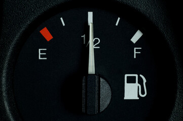 The indicator on the car panel, half of the fuel tank. Close-up. Fuel gauge indicating half