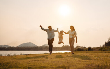 Fototapeta premium Happy Family enjoying a peaceful walk and running in a scenic field with a serene lake in the background.