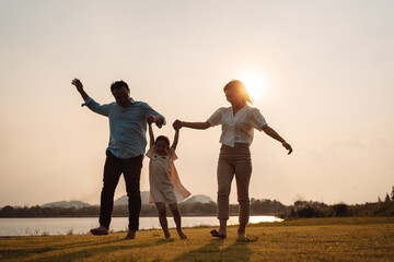 Happy Family enjoying a peaceful walk and running in a scenic field with a serene lake in the background.