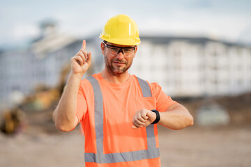 Worker in building uniform on buildings construction background. Builder at the construction site....