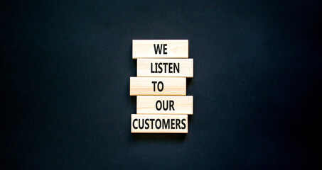 We listen to our customers symbol. Concept words We listen to our customers on wooden block. Beautiful black table black background. Business we listen to our customers concept. Copy space.