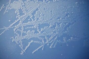 Weißes Eismuster auf weißer Metallfläche bei Sonne, Frost und Schnee am Morgen im Winter