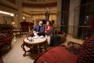 Man and woman with laptop communicate in cozy relaxation area