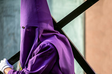 Nazareno with the cross and the hood in the Good Friday procession of Holy Week in Murcia, Spain dressed in purple