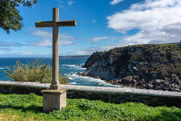 Stone cross in front of the cliffs of the Cantabrian Sea in the tourist town of Luarca, Asturias.