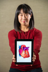 Woman holding a screen with a heart.