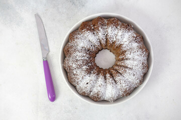 Chockolate cake with purple knife on gray background.