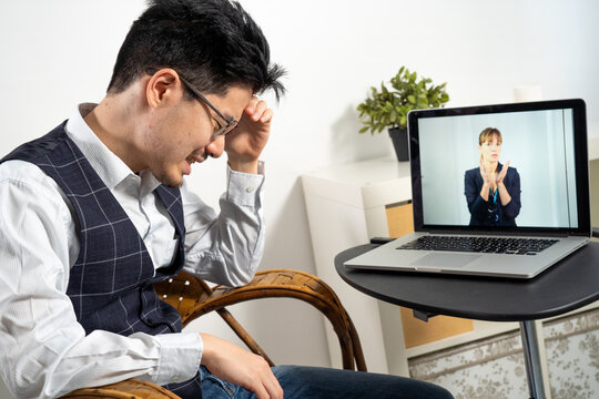 Female Doctor In Remote Consultation With 30 Year Old Patient With Head Pain.