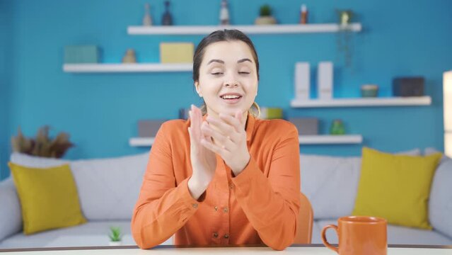 Young entrepreneur woman working in home office applauding and congratulating the good news.
Young entrepreneur young woman working from home looking at camera and rejoicing and applauding at good new