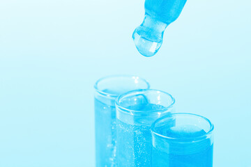 Glass flasks with blue liquid flowing out. Pipette.  dripping. Glitter, varnish, liquid. Sequins. Laboratory research of cosmetics and liquids. Current naked gel.
