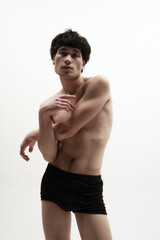 Fototapeta premium Portrait of young asian man posing in black underwear against white studio background. Relief, fit, strong male body. Concept of male body aesthetics, style, fashion, health, men's beauty
