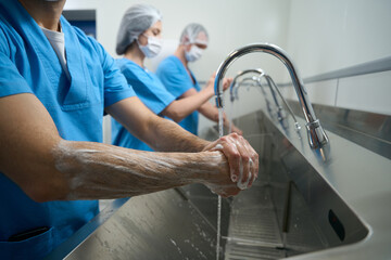 Team of surgeons thoroughly washes their hands before surgery