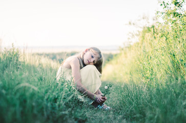 Naklejka na ściany i meble sad child outdoors in countryside sitting in grass
