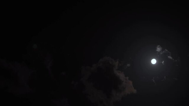 Clouds passing in front of the moon at night