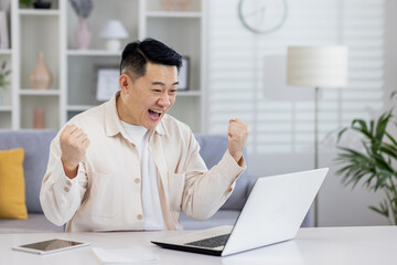 Asian working remotely from home office with laptop, businessman received notification of good achievement results, freelancer satisfied with work rejoices and celebrates victory and triumph.