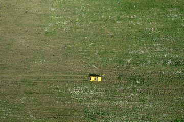 Top view of a yellow retro car on the summer green meadow field with white flowers distant plan