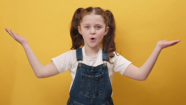 Portrait of excited amazed little girl kid looking shocked surprised wow showing hands brain explosion gesture, posing isolated over yellow color background wall in studio. People emotion concept