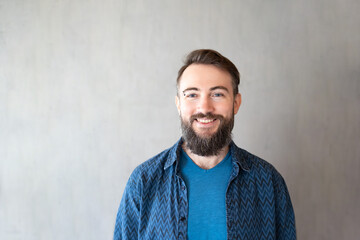 Close-up portrait of bearded biracial handsome young man with eyebrow piercing smiling against grey wall, copy space - Powered by Adobe