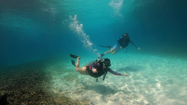 Under Water scuba film from Ko Tao island in southern Thailand - two divers at shallow depth - beautyful sunlight and sandy ocean floor