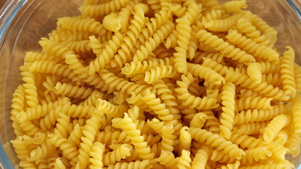 pâtes fusilli crues en gros plan, sur un plat	