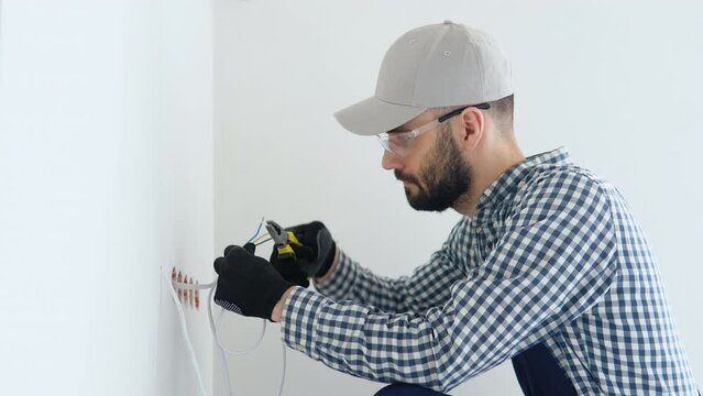 Electrician installs decorative frame on electric and TV sockets
