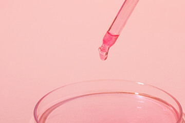 Pipette with dripping pink liquid. Or rose gold. On top of a Petri dish with pink liquid. On a pink background. Laboratory, chemistry, medicine. Cosmetic research. glitter.
