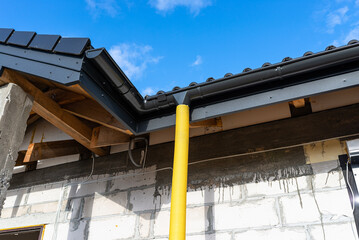 100mm diameter yellow PVC pipe connected to the end of the gutter on the roof, protected against...