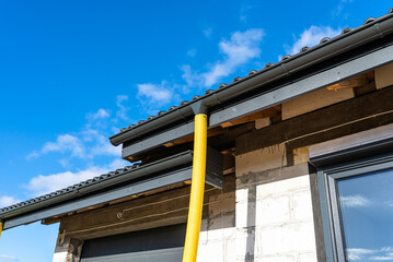 100mm diameter yellow PVC pipe connected to the end of the gutter on the roof, protected against water.